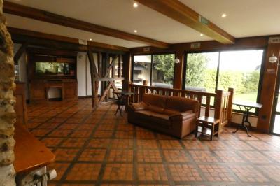 Salle de bain lumineuse avec baignoire encastrée sur estrade carrelée, poutres apparentes et grande fenêtre.
