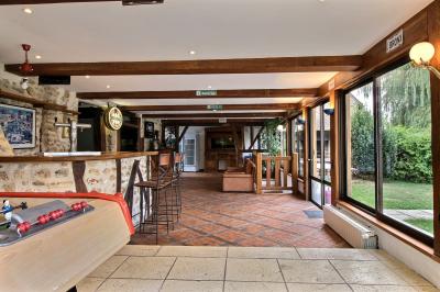 Salle de bain lumineuse avec baignoire encastrée sur estrade carrelée, poutres apparentes et grande fenêtre.