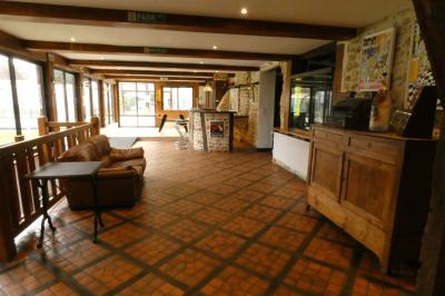 Salle de bain lumineuse avec baignoire encastrée sur estrade carrelée, poutres apparentes et grande fenêtre.