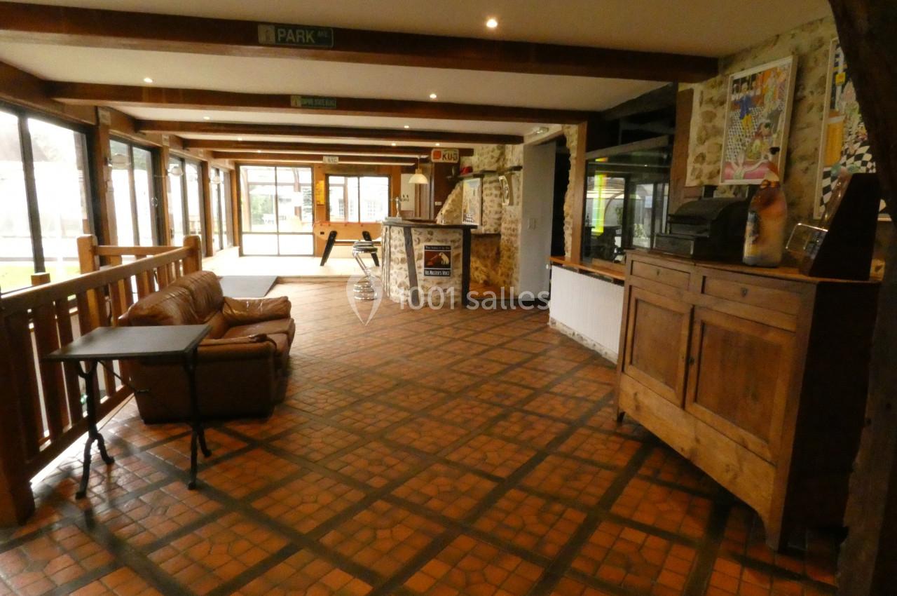 Intérieur d'un espace avec canapé, comptoir en pierre, meubles en bois et grandes baies vitrées donnant sur l'extérieur.