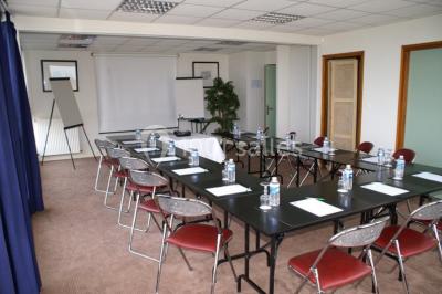 Terrasse extérieure avec tables et chaises en métal sur un sol en gazon synthétique, entourée de verdure.