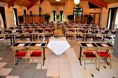 Terrasse extérieure avec tables et chaises en métal sur un sol en gazon synthétique, entourée de verdure.