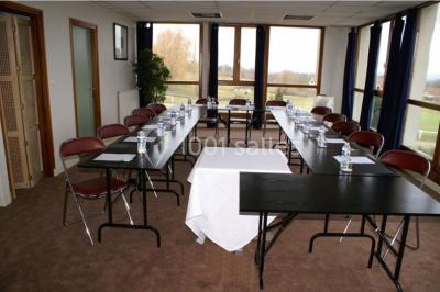 Terrasse extérieure avec tables et chaises en métal sur un sol en gazon synthétique, entourée de verdure.