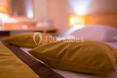 Terrasse extérieure avec tables et chaises en métal sur un sol en gazon synthétique, entourée de verdure.