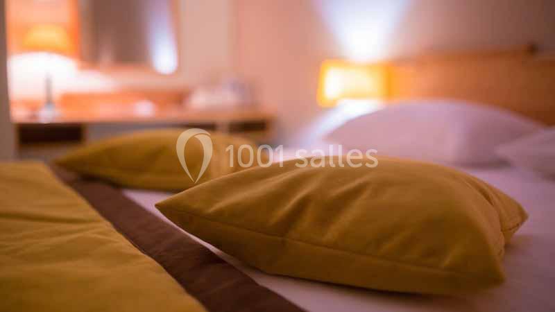 Deux oreillers jaunes posés sur un lit avec une lampe allumée en arrière-plan.