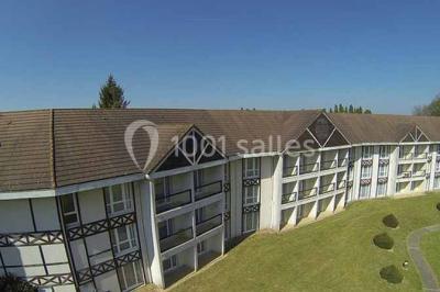 Terrasse extérieure avec tables et chaises en métal sur un sol en gazon synthétique, entourée de verdure.