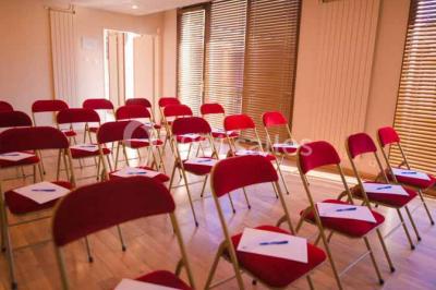 Terrasse extérieure avec tables et chaises en métal sur un sol en gazon synthétique, entourée de verdure.