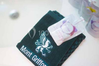 Terrasse extérieure avec tables et chaises en métal sur un sol en gazon synthétique, entourée de verdure.