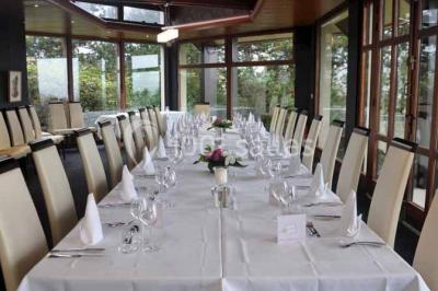 Terrasse extérieure avec tables et chaises en métal sur un sol en gazon synthétique, entourée de verdure.