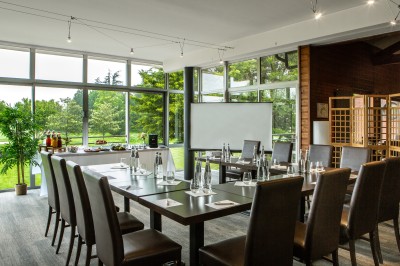 Table dressée en extérieur avec boissons et verres, sur une terrasse en bois surplombant un terrain de golf verdoyant.