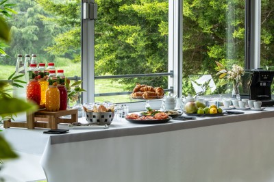Table dressée en extérieur avec boissons et verres, sur une terrasse en bois surplombant un terrain de golf verdoyant.