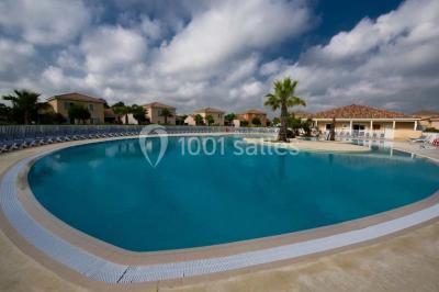Salle à manger lumineuse avec table en bois, chaises colorées, cuisine ouverte et décoration sobre.