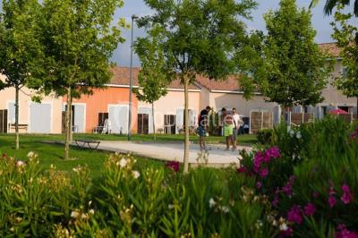 Salle à manger lumineuse avec table en bois, chaises colorées, cuisine ouverte et décoration sobre.