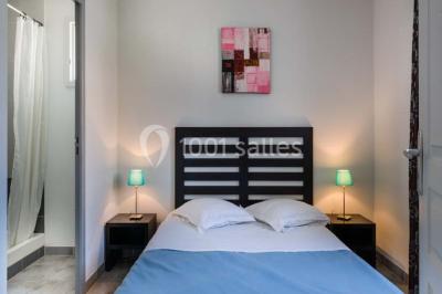 Salle à manger lumineuse avec table en bois, chaises colorées, cuisine ouverte et décoration sobre.