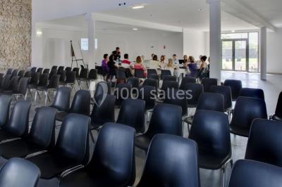 Salle à manger lumineuse avec table en bois, chaises colorées, cuisine ouverte et décoration sobre.
