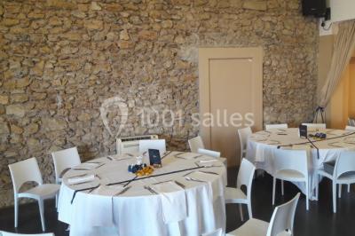 Salle à manger lumineuse avec table en bois, chaises colorées, cuisine ouverte et décoration sobre.