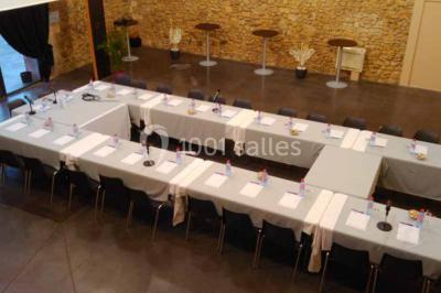 Salle à manger lumineuse avec table en bois, chaises colorées, cuisine ouverte et décoration sobre.