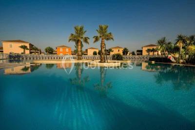 Salle à manger lumineuse avec table en bois, chaises colorées, cuisine ouverte et décoration sobre.