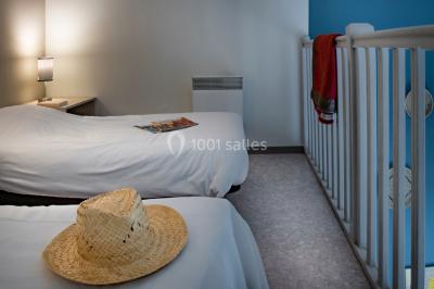 Salle à manger lumineuse avec table en bois, chaises colorées, cuisine ouverte et décoration sobre.