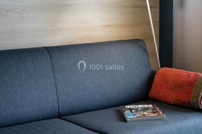 Salle à manger lumineuse avec table en bois, chaises colorées, cuisine ouverte et décoration sobre.