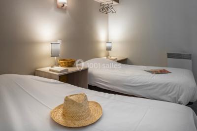 Salle à manger lumineuse avec table en bois, chaises colorées, cuisine ouverte et décoration sobre.