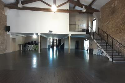 Salle à manger lumineuse avec table en bois, chaises colorées, cuisine ouverte et décoration sobre.