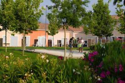 Salle à manger lumineuse avec table en bois, chaises colorées, cuisine ouverte et décoration sobre.
