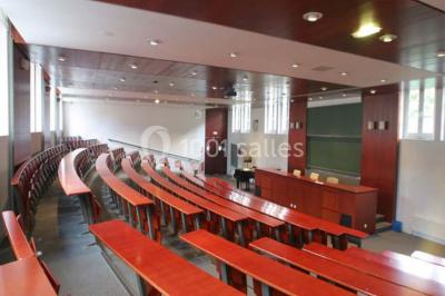Salle de restauration lumineuse avec de grandes baies vitrées, tables orange et bois, et chaises assorties.