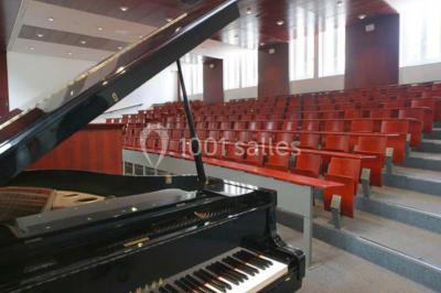 Salle de restauration lumineuse avec de grandes baies vitrées, tables orange et bois, et chaises assorties.