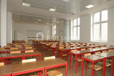 Salle de restauration lumineuse avec de grandes baies vitrées, tables orange et bois, et chaises assorties.