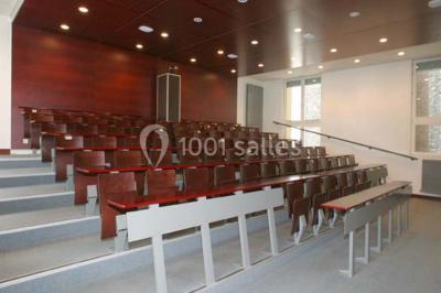 Salle de restauration lumineuse avec de grandes baies vitrées, tables orange et bois, et chaises assorties.