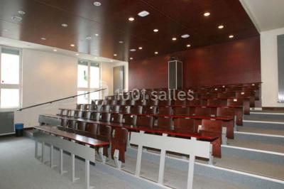 Salle de restauration lumineuse avec de grandes baies vitrées, tables orange et bois, et chaises assorties.