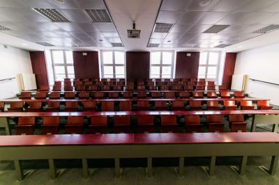Salle de restauration lumineuse avec de grandes baies vitrées, tables orange et bois, et chaises assorties.