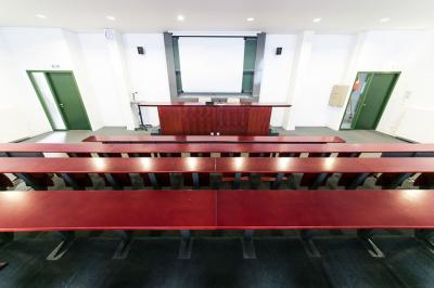Salle de restauration lumineuse avec de grandes baies vitrées, tables orange et bois, et chaises assorties.