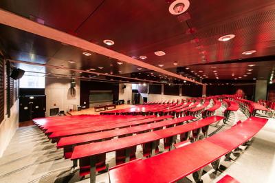 Salle de restauration lumineuse avec de grandes baies vitrées, tables orange et bois, et chaises assorties.