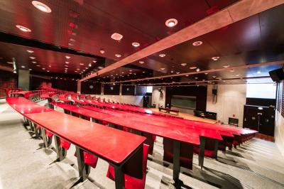 Salle de restauration lumineuse avec de grandes baies vitrées, tables orange et bois, et chaises assorties.