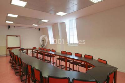 Salle de restauration lumineuse avec de grandes baies vitrées, tables orange et bois, et chaises assorties.
