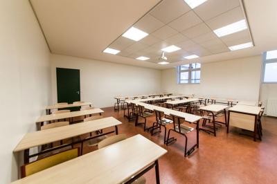 Salle de restauration lumineuse avec de grandes baies vitrées, tables orange et bois, et chaises assorties.
