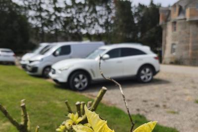 Façade en pierre d'un château bordé par un cours d'eau, avec un pont en arc et des arbres environnants.