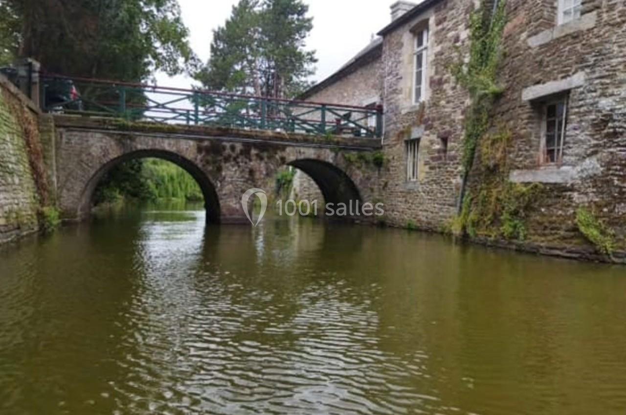 Pont en pierre avec deux arches au-dessus d'une rivière, entouré de bâtiments en pierre et de végétation.