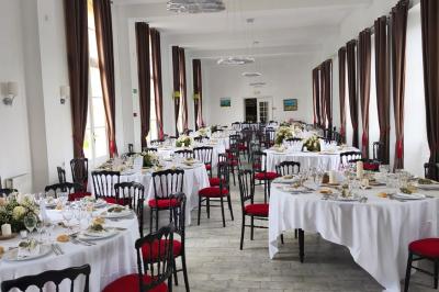 Façade en pierre d'un château bordé par un cours d'eau, avec un pont en arc et des arbres environnants.