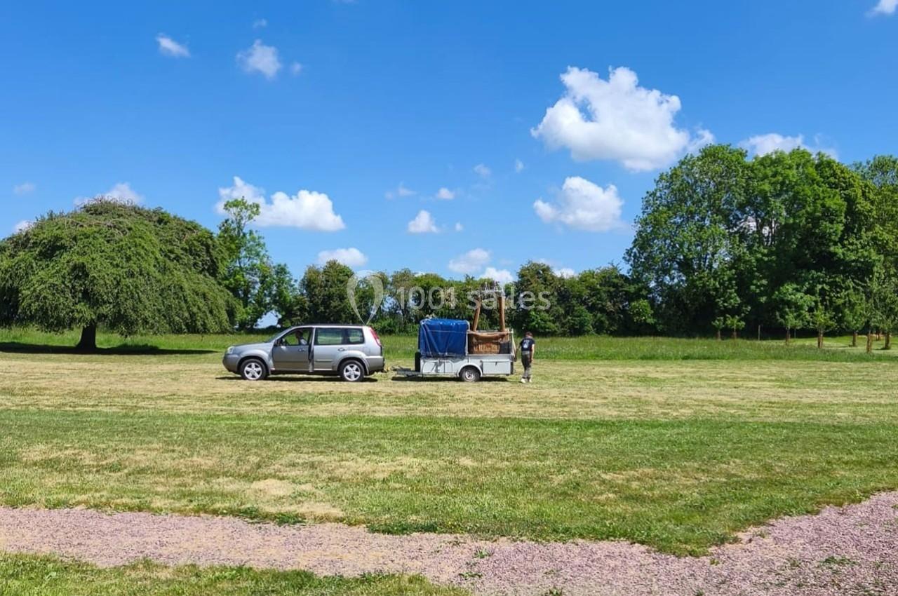 Un véhicule avec une remorque contenant un équipement est stationné dans un champ sous un ciel dégagé.