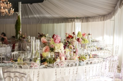 Un photographe capture une cérémonie sous une pergola décorée de fleurs blanches, entourée de verdure et de rochers.