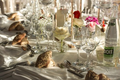 Un photographe capture une cérémonie sous une pergola décorée de fleurs blanches, entourée de verdure et de rochers.