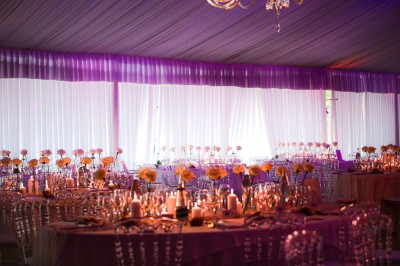 Un photographe capture une cérémonie sous une pergola décorée de fleurs blanches, entourée de verdure et de rochers.