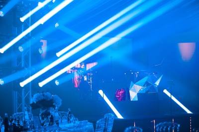 Un photographe capture une cérémonie sous une pergola décorée de fleurs blanches, entourée de verdure et de rochers.