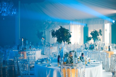 Un photographe capture une cérémonie sous une pergola décorée de fleurs blanches, entourée de verdure et de rochers.