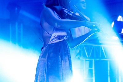 Un photographe capture une cérémonie sous une pergola décorée de fleurs blanches, entourée de verdure et de rochers.