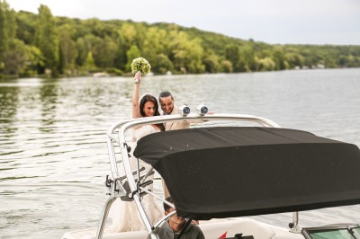 Un photographe capture une cérémonie sous une pergola décorée de fleurs blanches, entourée de verdure et de rochers.