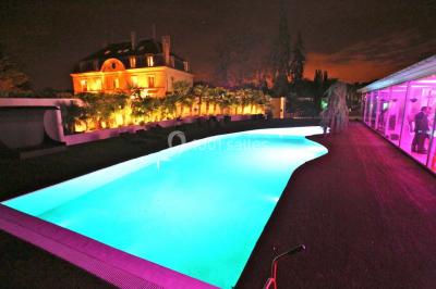 Salle de bain avec une cabine de douche moderne, un banc en bois intégré, deux vasques noires et une fenêtre avec stores.